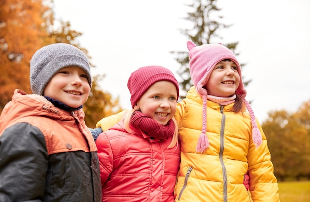 kindheit, freizeit, freundschaft und menschenkonzept - gruppe glücklicher kinder, die sich im herbstpark umarmen