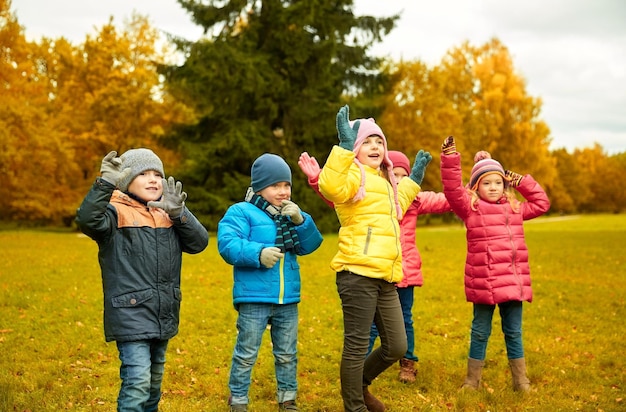 kindheit, freizeit, freundschaft und personenkonzept - gruppe glücklicher kinder, die spiel spielen und spaß im herbstpark haben