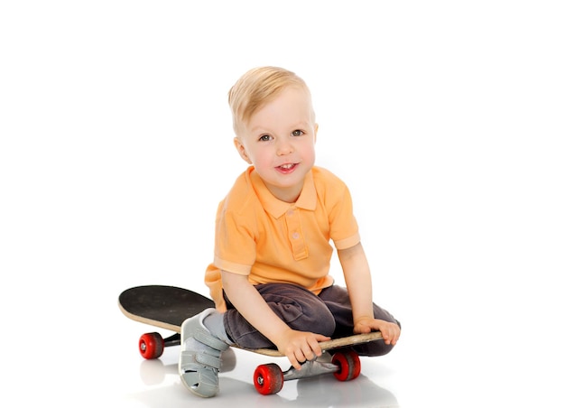 kindheit, sport, freizeit und personenkonzept - glücklicher kleiner junge, der auf skateboard sitzt