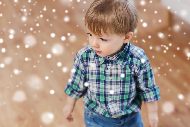 Kindheit und Menschenkonzept - glücklicher kleiner Junge zu Hause über Schnee