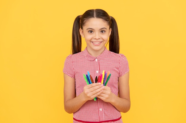 Kindheitsentwicklung und Bildung. Kreativität. zurück zur Schule. Fröhliches Teenager-Mädchen, das Bild zeichnen wird. Kind hält bunte Stifte. lächelndes Kind mag Zeichnen und Malen.