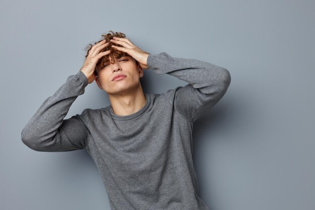 Kinky guy en un estilo de vida de estudio de moda de sudadera gris inalterado