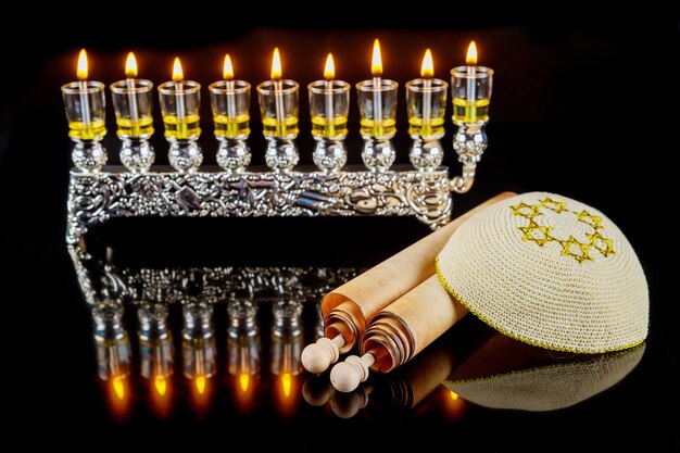 Kippah y totah para Hanukkah en menorá con fondo de velas de aceite ardiente. Fiesta judía.