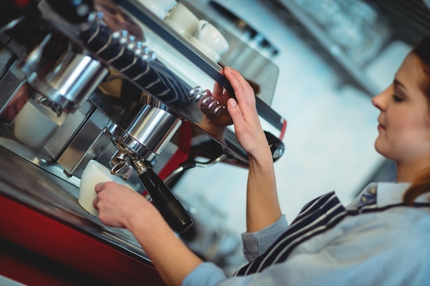 Kippen Sie Schuss von barista unter Verwendung der Espressomaschine, um Kaffee in der Schale zu gießen