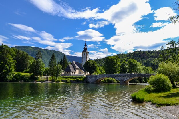 Kirche am Ufer eines Bergsees und eine alte Steinbrücke über den Fluss.