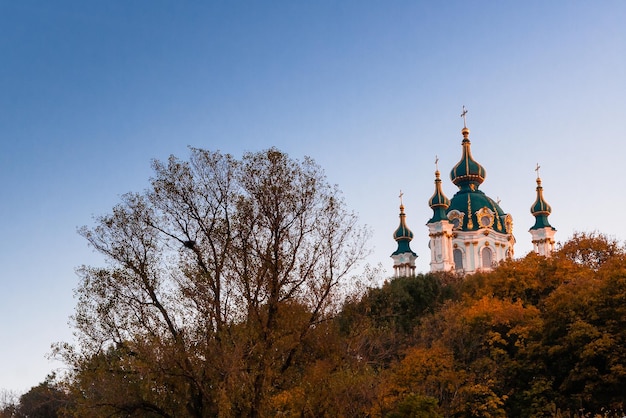 Kirche auf einem Hintergrund von Herbstbäumen und blauem Himmel