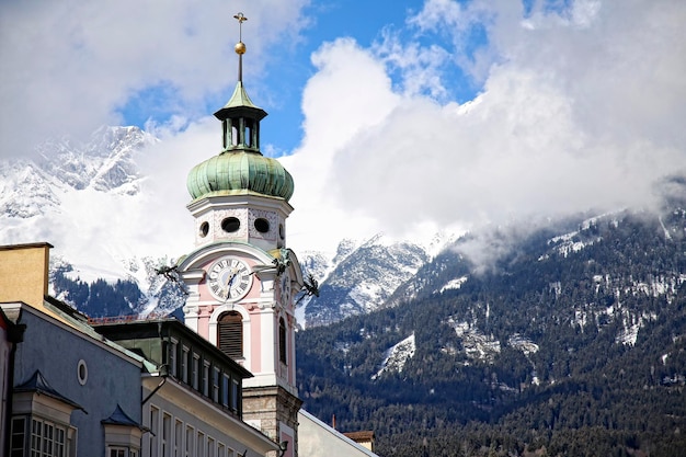 Kirchturm und Hintergrund die schneebedeckten Berge der Stadt Innsbruck Österreich
