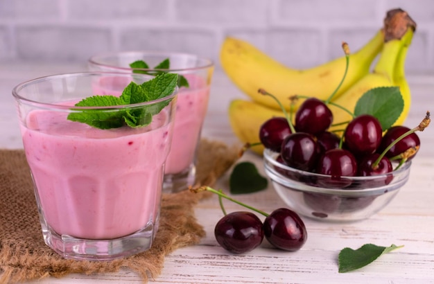 Kirsch- und Bananen-Smoothie auf weißem Holzhintergrund.