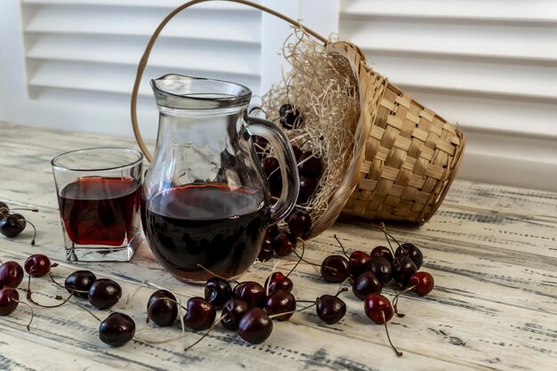 Kirsch- und Kirschsaft oder Wein auf einem Holztisch ein Dekanter und ein Glas mit Saft