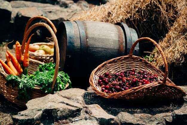 Kirschbeeren in einem Weidenkorb, ein Bündel Karotten und ein Fass Wein stehen auf dem Heuboden