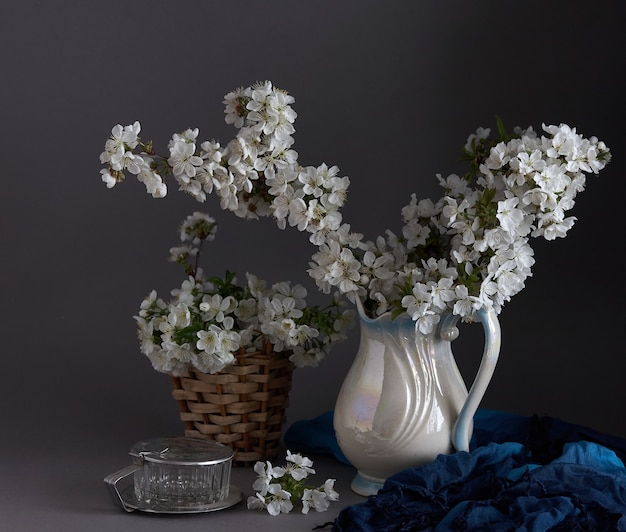 Kirschblüten in der weißen Vase auf grauem Hintergrund