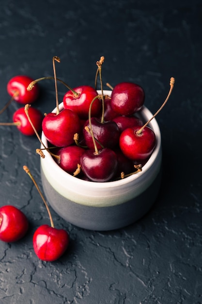 Kirschen in einer Schüssel auf schwarzem Hintergrund Süße frische rote Kirschen in Keramikschale auf schwarzem Steinhintergrund Früchte gesunde Ernährung