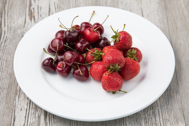 Kirschfrucht und weißer Holzhintergrund Fruchtsalat mit Erdbeer-Heidelbeer-Süßkirsche