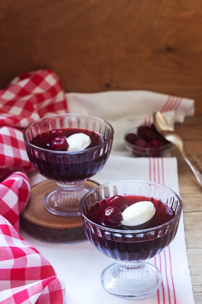 Kirschgelee mit Sahne und Beeren auf einem Holztisch. Rustikaler Stil.