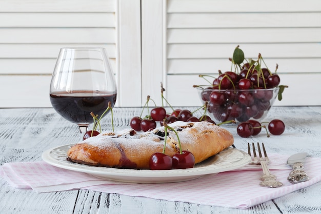 Kirschkäsekuchen serviert auf einem Bonbonteller mit Rotwein