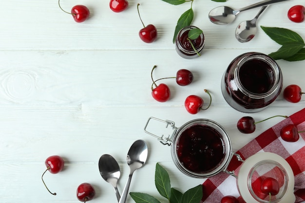 Kirschmarmelade und Zutaten auf weißem Holztisch