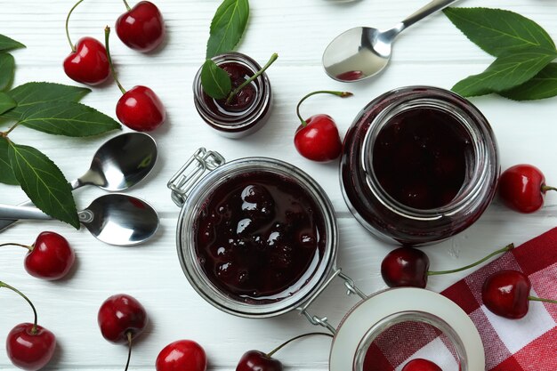 Kirschmarmelade und Zutaten auf weißem Holztisch