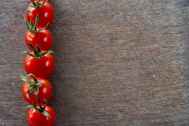 Kirschtomate, die Seitenrahmen auf zerkratztem hölzernem Hintergrund bildet