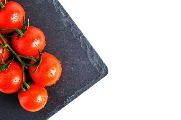 Kirschtomaten auf einem Schiefer-Schneidebrett isolieren auf weißem Hintergrund