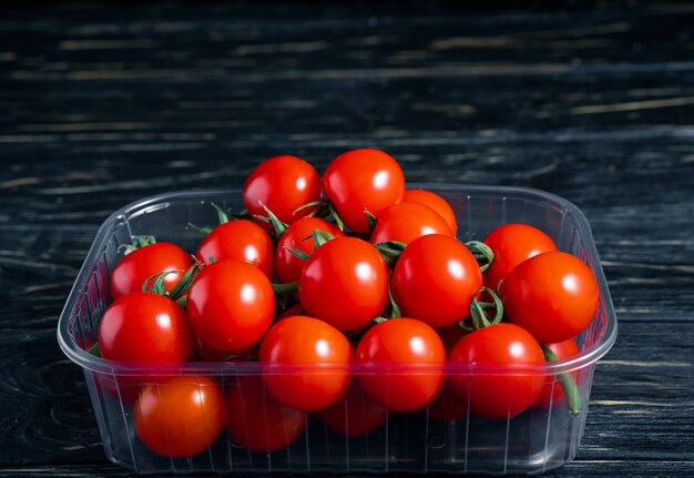 Kirschtomaten im Plastikkasten auf dem Holztisch