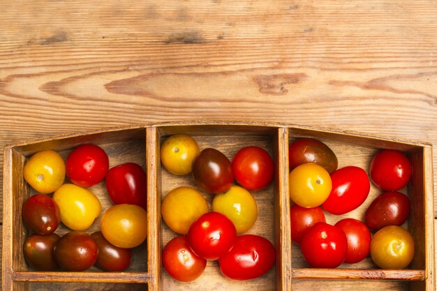 Kirschtomaten in einer Holzkiste auf einem Holztisch in Draufsicht