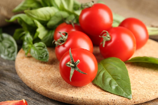 Kirschtomaten mit Basilikum auf Holztisch schließen oben