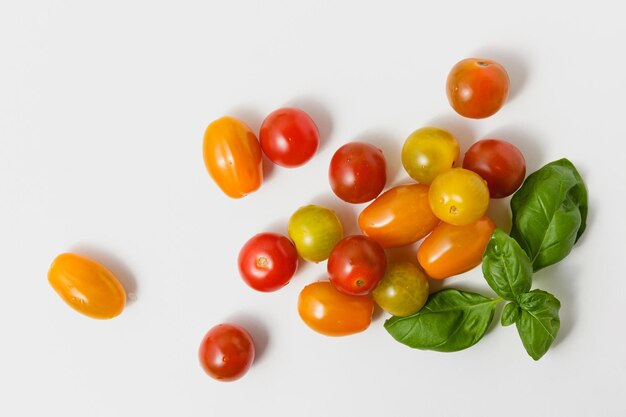 Kirschtomaten mit grünem Basilikum auf weißem Hintergrund