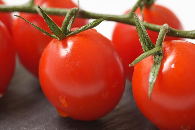 Kirschtomaten mit grünen Blättern auf dunklem Teller