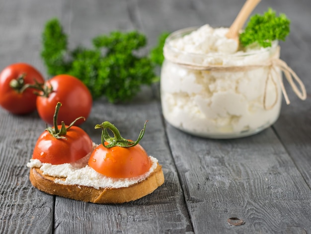 Kirschtomaten mit Quark und geröstetem Brot auf einem Holztisch.