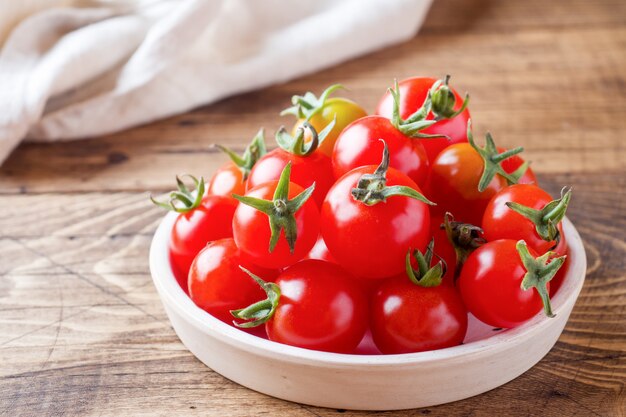 Kirschtomaten rot in der keramischen Schüssel auf Holztisch.