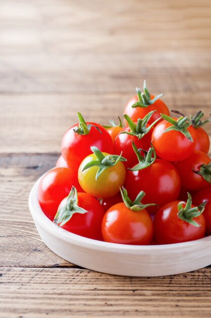 Kirschtomaten rot in der keramischen Schüssel auf Holztisch.