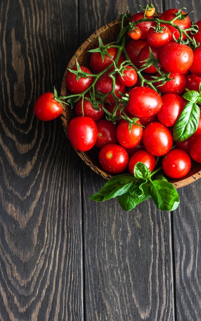 Kirschtomaten und -basilikum in einer hölzernen Platte.