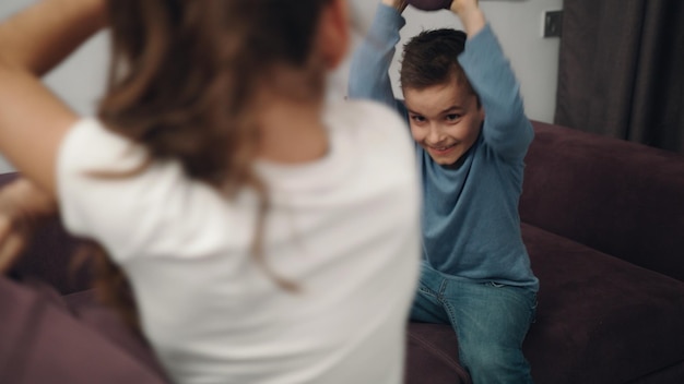 Kissenschlacht für Kinder Nahaufnahme von glücklichen Geschwistern, die auf dem Sofa gegen Kissen kämpfen