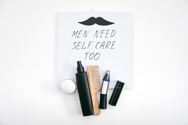 Kit de autocuidado para hombres con productos y dispositivos para el cuidado de la belleza masculina y pizarrón con el texto que los hombres necesitan