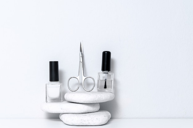 Kit de acessórios para casa ou salão de manicure com polonês, tesoura, tesoura em pano de fundo de pedra branco.