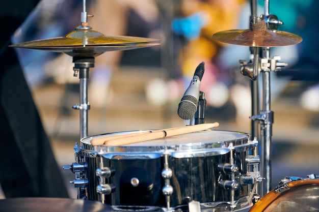 Kit de bateria em baquetas de festa de rock ao ar livre no tambor tomtom Conjunto de bateria com baquetas prontas para tocar música no desempenho de rock ao ar livre de verão close-up