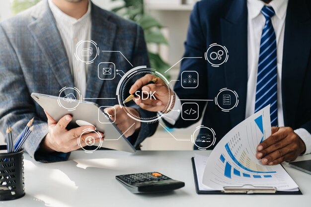 Kit de desarrollo de software SDK concepto de tecnología de lenguaje de programación Persona que escribe computadora portátil y tableta con icono SDK en pantalla virtual en la oficina