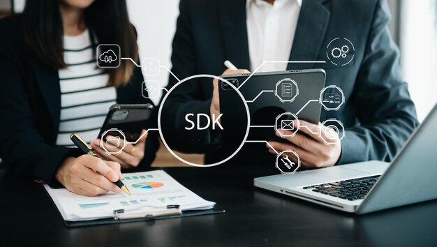 Kit de desarrollo de software SDK concepto de tecnología de lenguaje de programación Persona que escribe computadora portátil y tableta con icono SDK en pantalla virtual en la oficina