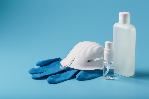 Kit de protección antivirus sobre fondo azul, máscara, guantes de goma, botellas de desinfectante para manos, gel antiséptico.