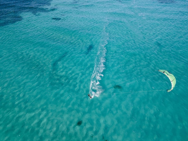 Kite surfista cabalgando sobre una vista aérea tropical de aguas turquesas claras