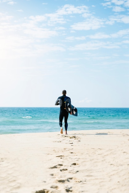 Kitesurfer de homem bonito correndo na praia.