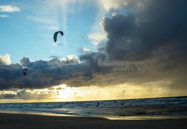 Foto kitesurfer en el mar báltico al atardecer antes de la lluvia en hermosas nubes de lluvia a la luz del sol