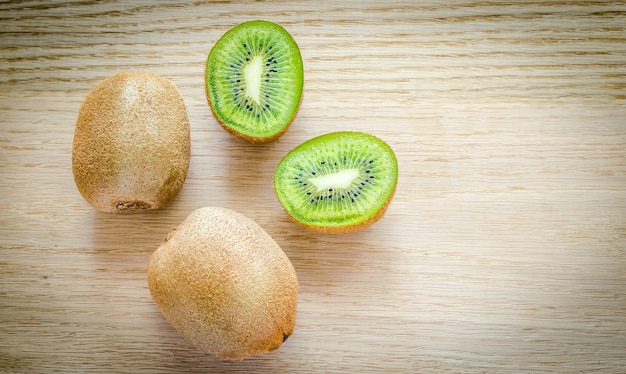 Kiwi auf dem Holz: ganze Frucht und Querschnitt