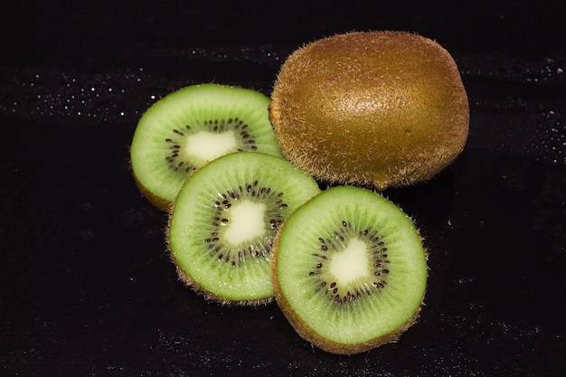 Kiwi auf schwarzem Hintergrund mit Wassertropfen