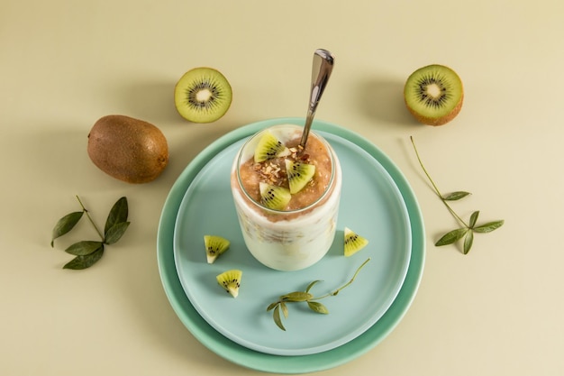 Kiwi-Bananen- und Nuss-Smoothies in einem modernen Glas auf einer Keramikplatte und pastellfarbenem Hintergrund mit Kiwi-Frucht ein gesundes Bio-Frühstück oder ein Snack