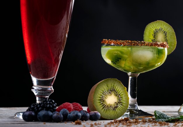 Kiwi-Cocktail mit Scheiben und Früchten des Waldes auf Holzbasis dekoriert.