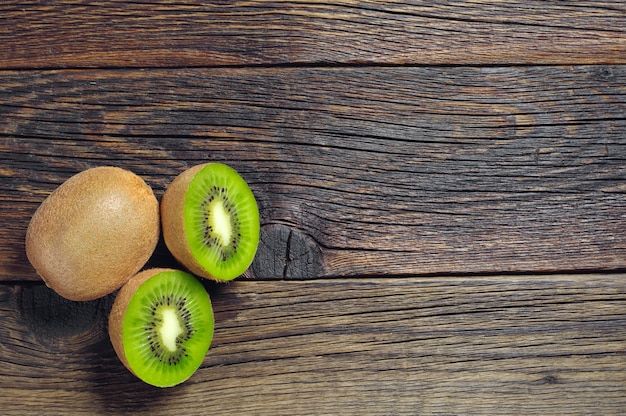 Kiwi com metade em fundo escuro de madeira, vista superior