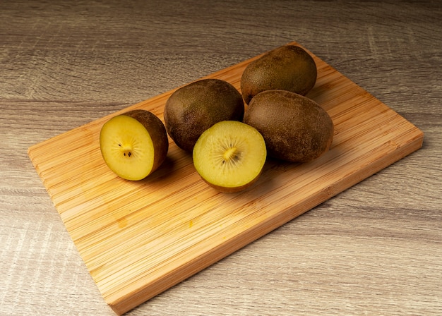 Kiwi dorado entero y en rodajas sobre mesa de madera, concepto de fruta y comida sana