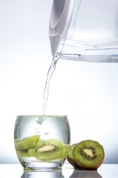 Foto kiwi em um copo e salpicos de água. comida saborosa e saudável. bebidas sazonais. horário de verão. frescura verde