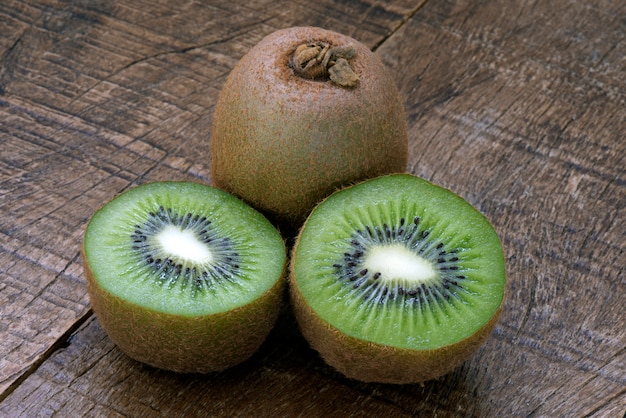 Kiwi entero y cortado en una mesa de madera rústica